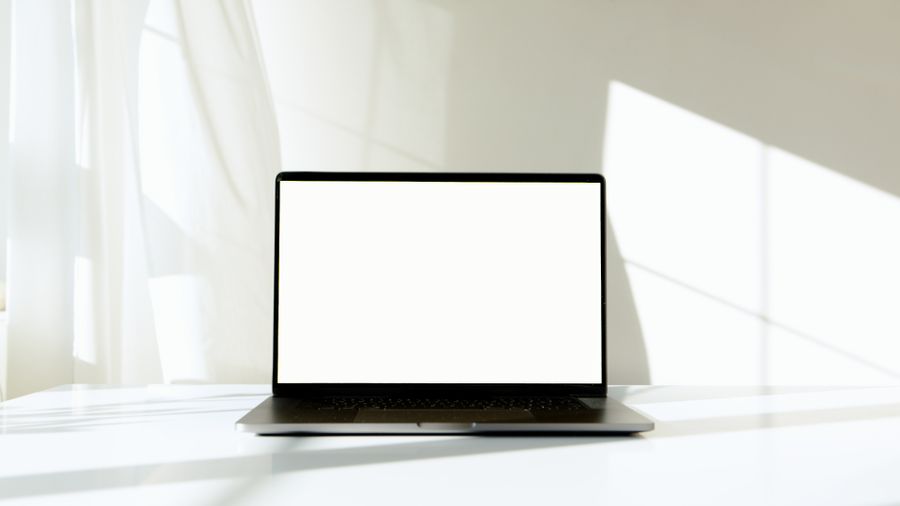 Laptop with a blank screen on a sunlit desk, styled to represent a freshly launched website.